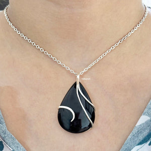 Black teardrop pendant necklace on a person's neck