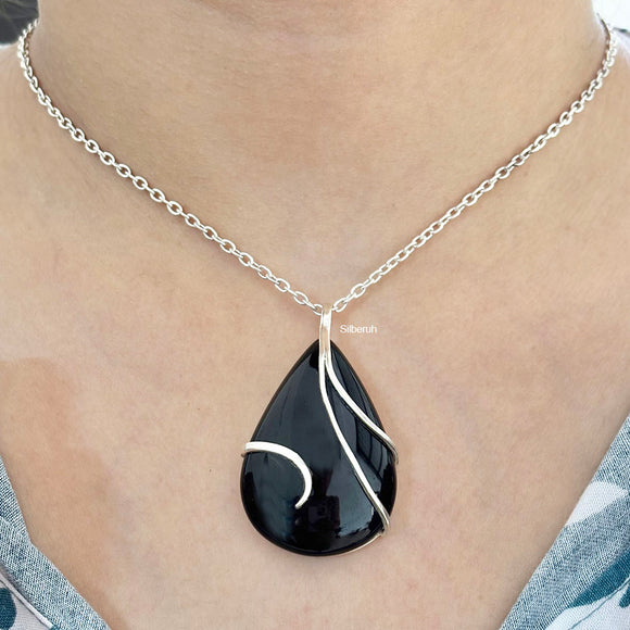 Black teardrop pendant necklace on a person's neck
