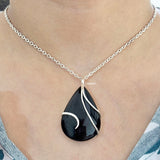 Black teardrop pendant necklace on a person's neck