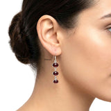 Close-up of natural garnet gemstones in a silver triple-drop earring