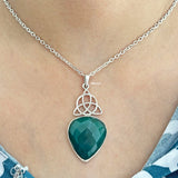 Necklace with a green onyx pendant and silver Celtic knot design on a person's neck.