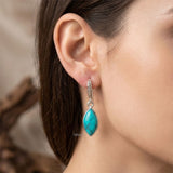 Turquoise teardrop earring worn by a person